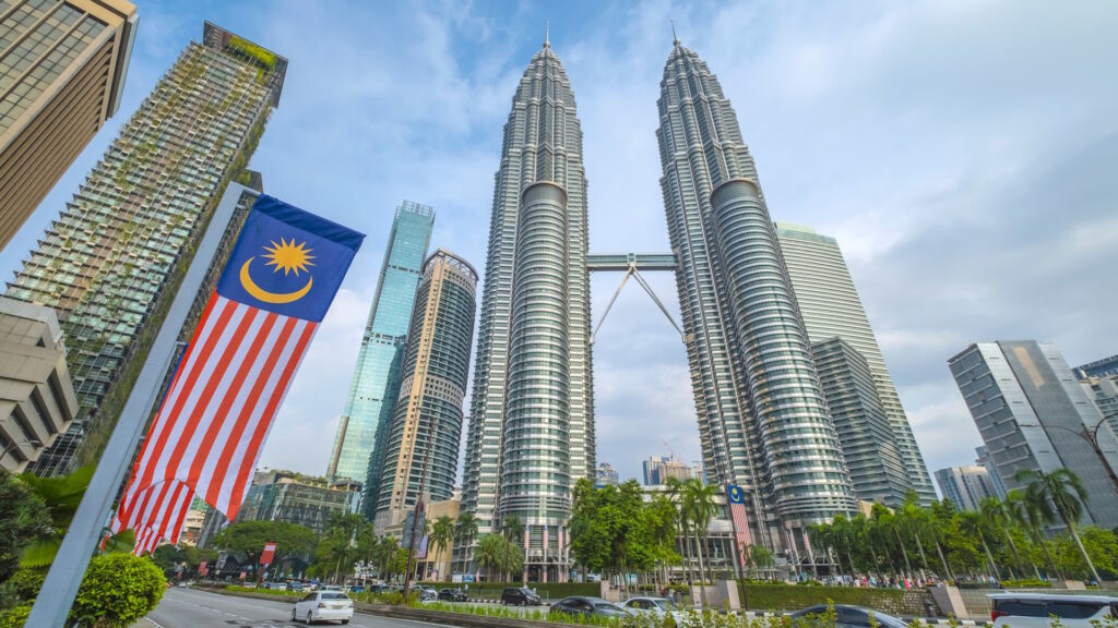 Malaysian Flag with the Petronas Towers and various buildings in the background in Kuala Lumpur, capital of Malaysia