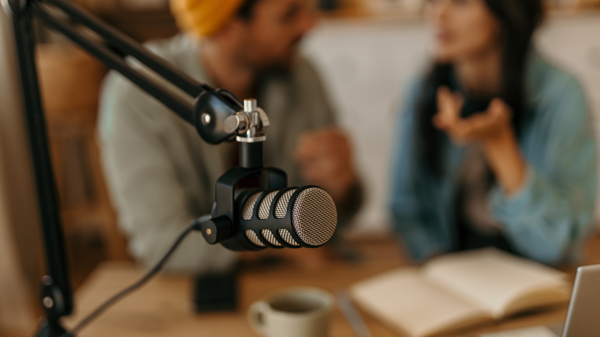 Microphone in front of 2 blurred people chatting in the background