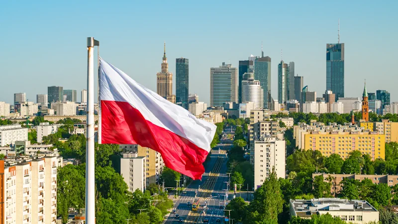 Polish flag waving in front of the skyline of Warsaw, capital of Poland