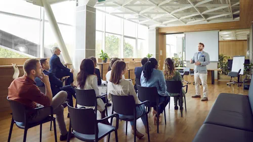 Trainer in front of 10 students in a business meeting room