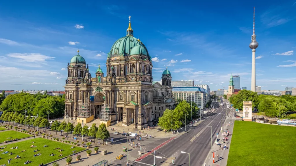 Aerial view of Berlin Cathedral in Lustgarten Park with the famous TV Tower in the background on a sunny day with blue sky and clouds in summer, Berlin Mitte district, Germany.