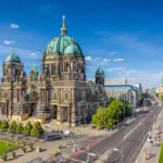 Aerial view of Berlin Cathedral in Lustgarten Park with the famous TV Tower in the background on a sunny day with blue sky and clouds in summer, Berlin Mitte district, Germany.
