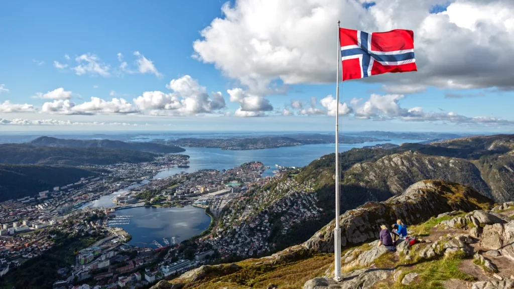 Flag of Norway waving in front of a panoramic view of Bergen, in Norway