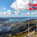 Flag of Norway waving in front of a panoramic view of Bergen, in Norway