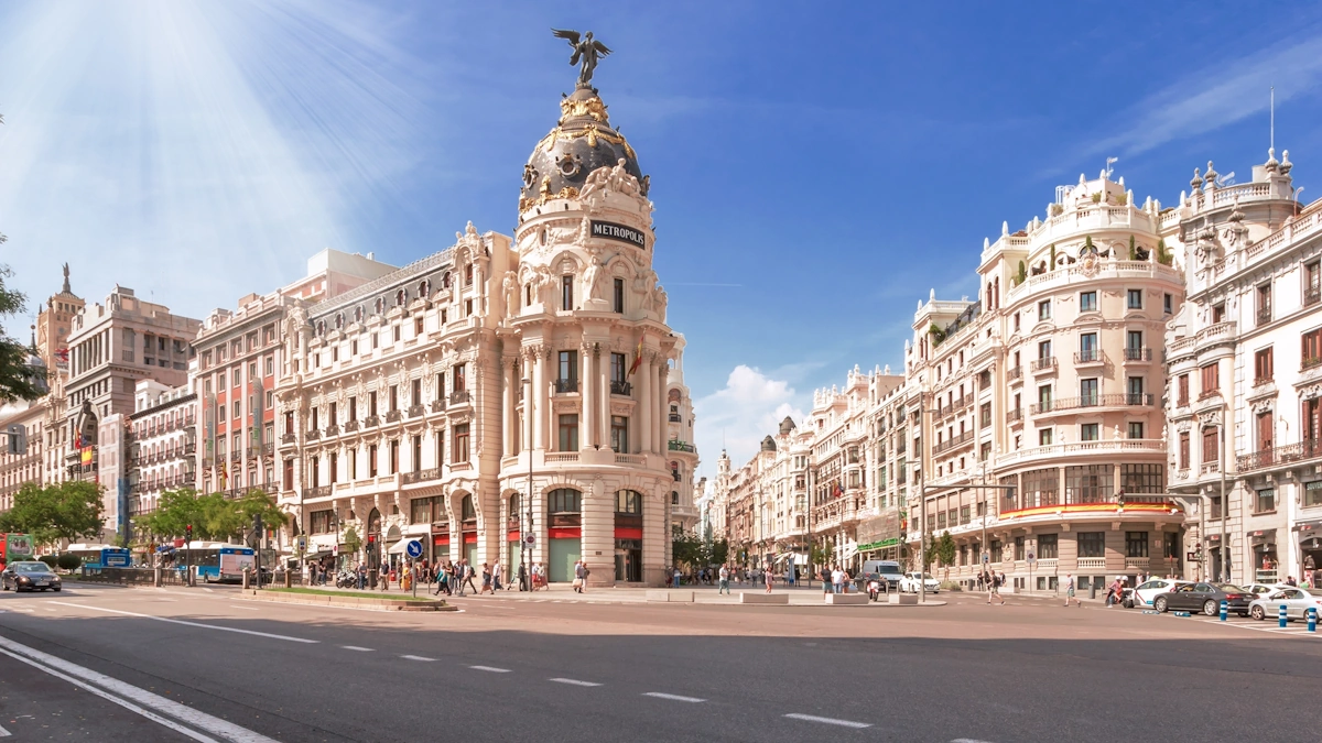 Iconic street view of Calle Alcalá and Gran Vía, showing a busy urban avenue with historic and modern buildings, traffic, and pedestrians on a clear day, in Madrid, capital of Spain