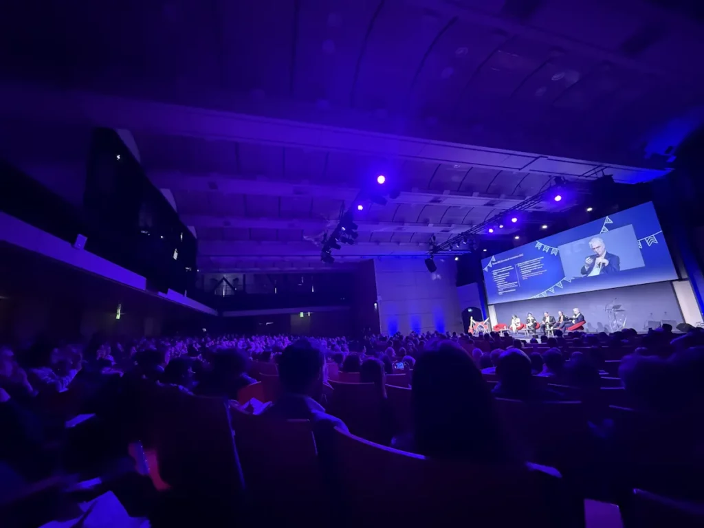 Rear view of the packed conference room during the JFE 2026 e-invoicing event in Paris, with attendees watching a presentation on stage.