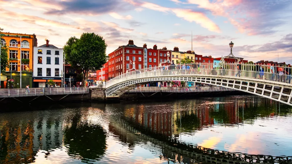 Evening view of the illuminated Ha’penny Bridge at sunset in Dublin, capital of Ireland