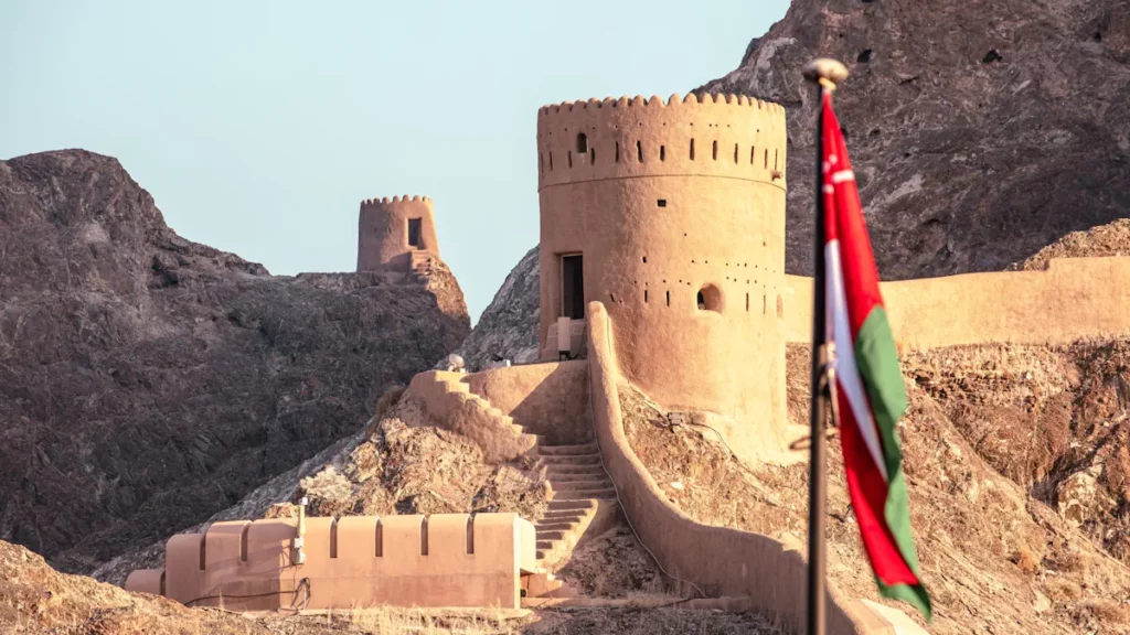 Mutrah Fort in Muscat, Sultanate of Oman, with the Omani flag displayed in the foreground.