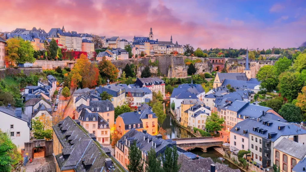 Panoramic view of Luxembourg City's Old Town and the Grund district, featuring historic buildings, stone bridges, and the Alzette River.