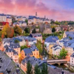 Panoramic view of Luxembourg City's Old Town and the Grund district, featuring historic buildings, stone bridges, and the Alzette River.
