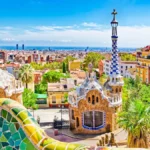 Panoramic view of Barcelona from Park Güell, featuring Gaudí’s colorful mosaic architecture and the city skyline.
