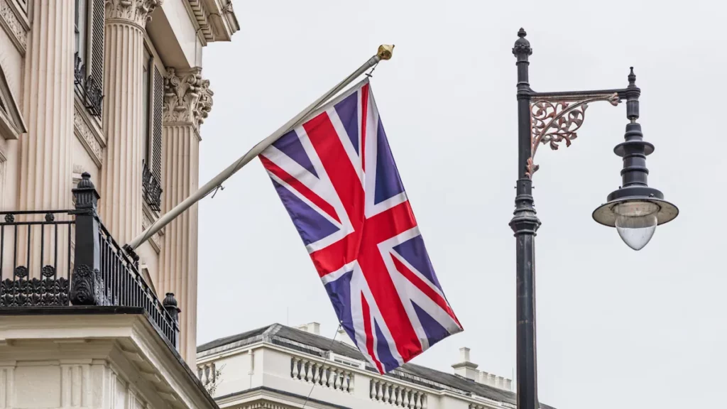 British Union Jack flying outside a classic London building beside a street lantern.